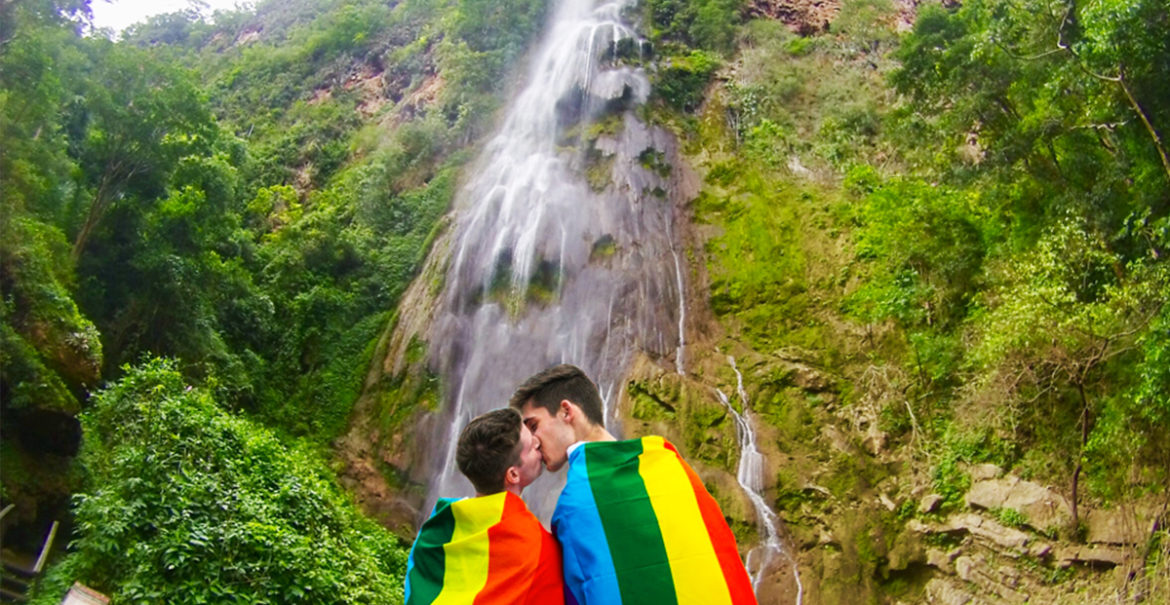 Casal posando com a bandeira LGBT em Bonito, MS