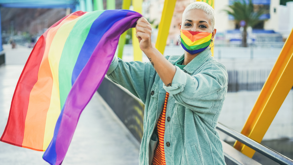 Mulher com máscara e bandeira LGBTQIA+