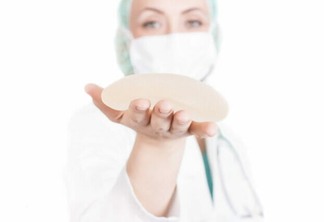A shallow focus shot of a female plastic surgeon holding a breast implant - plastic surgery concept