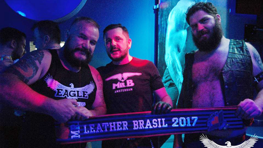 O organizador Tony Carlão segurando a faixa de couro do Mr Leather Brasil junto com os promoters Carlos Notari e Dan Barroso